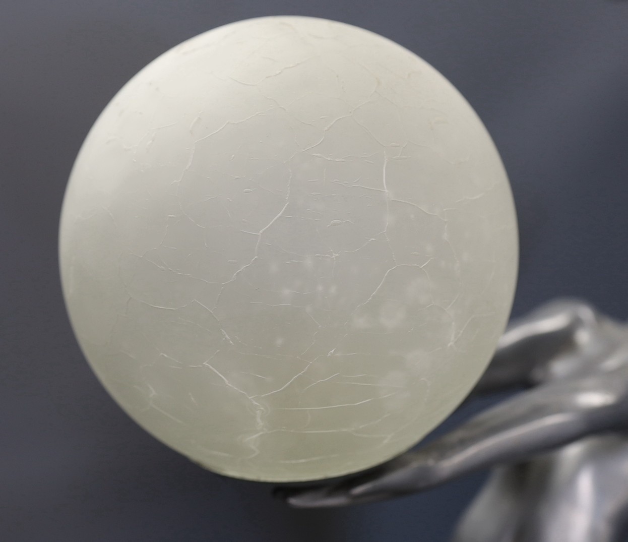 An Art Deco style figurative lamp of a lady holding a frosted glass globe, 66cms high.